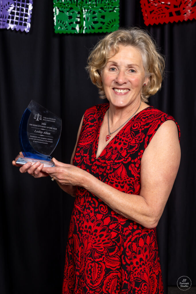 Lesley Allan, recipient of the 2026 Pro Bono Attorney of the Year. She is wearing a red dress holding the award